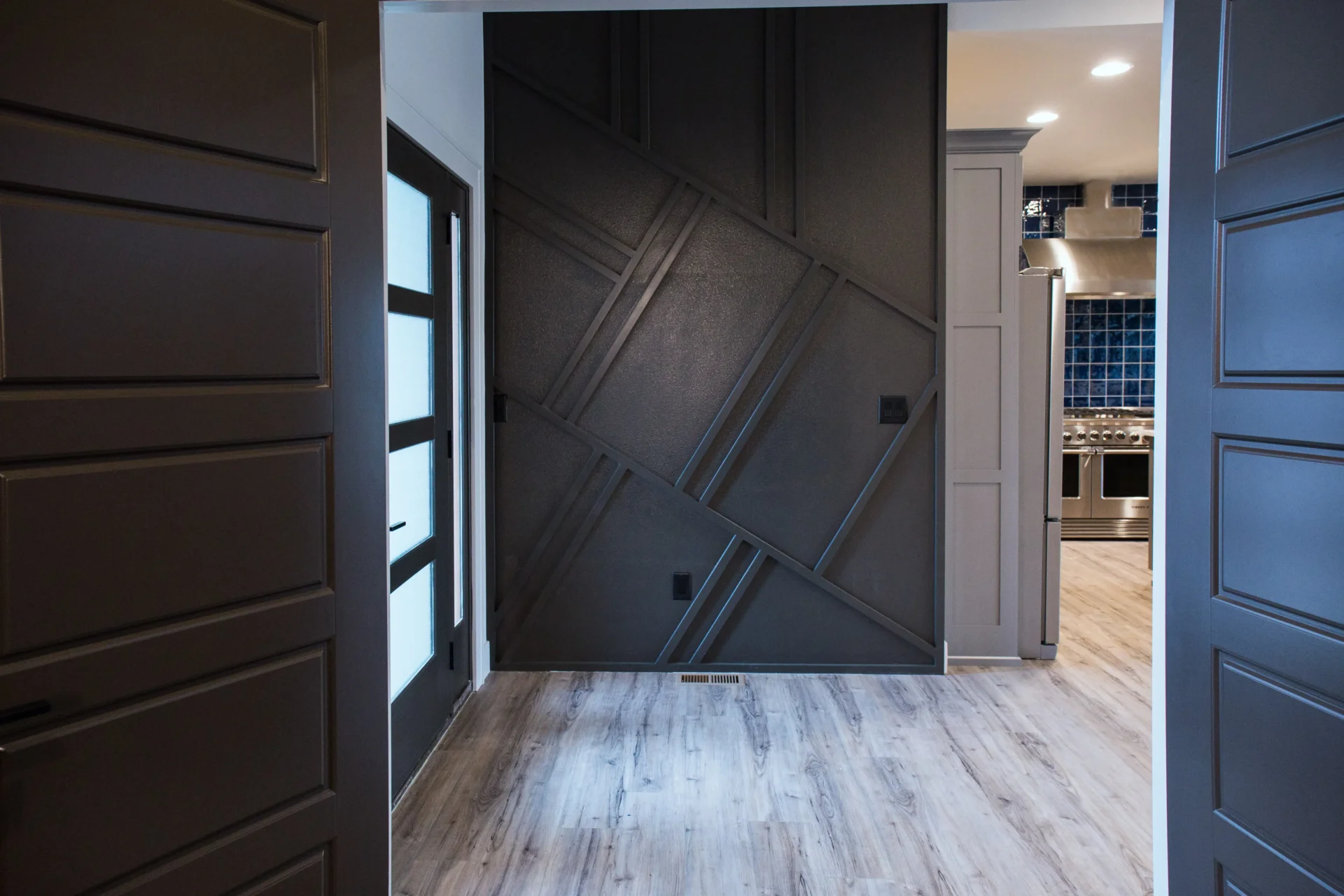 Room with textured wall black framed door and kitchen