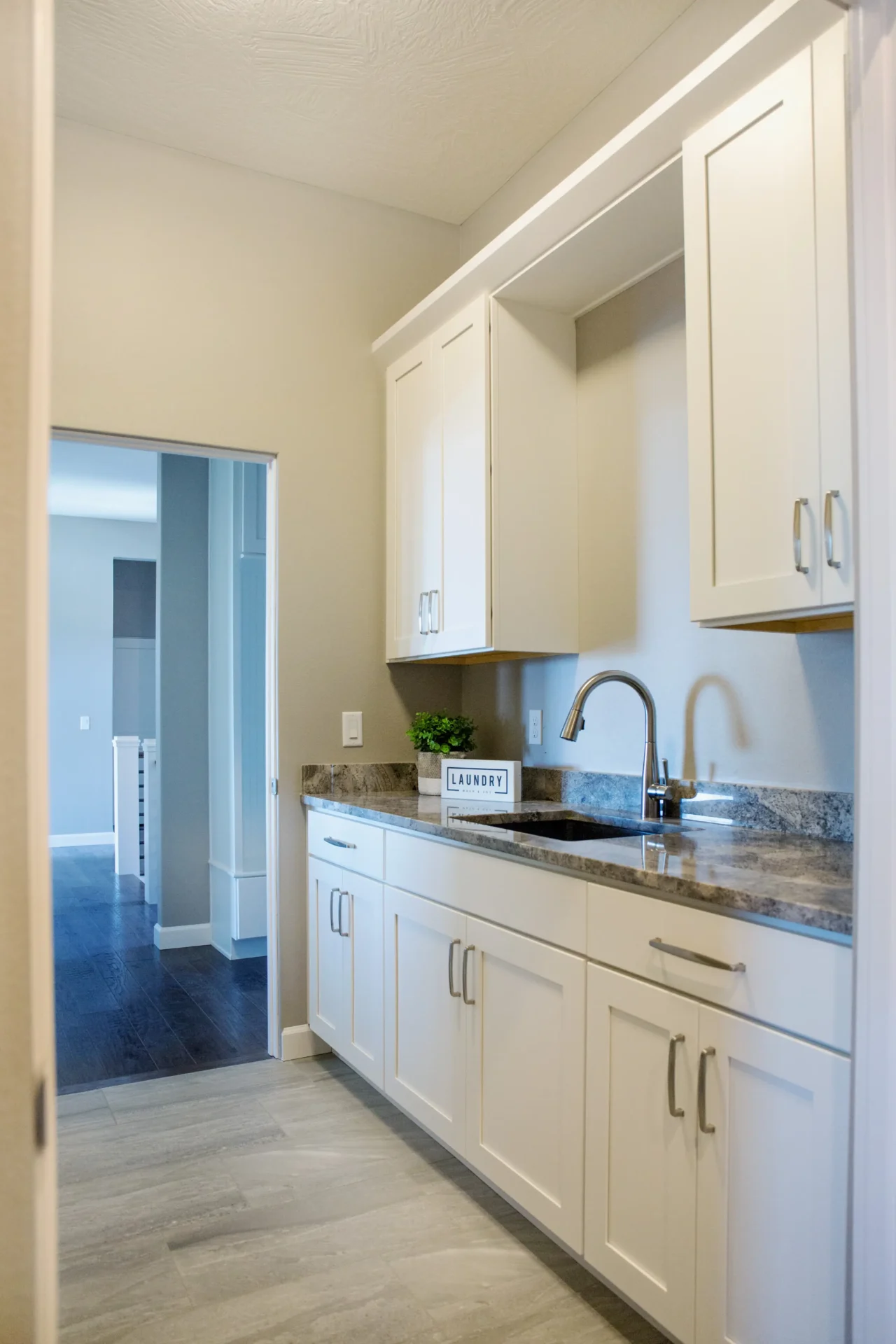 narrow white kitchen with sink and marble countertop