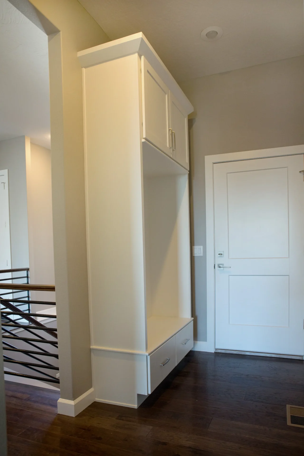 narrow hallway second level with white door and cabinet