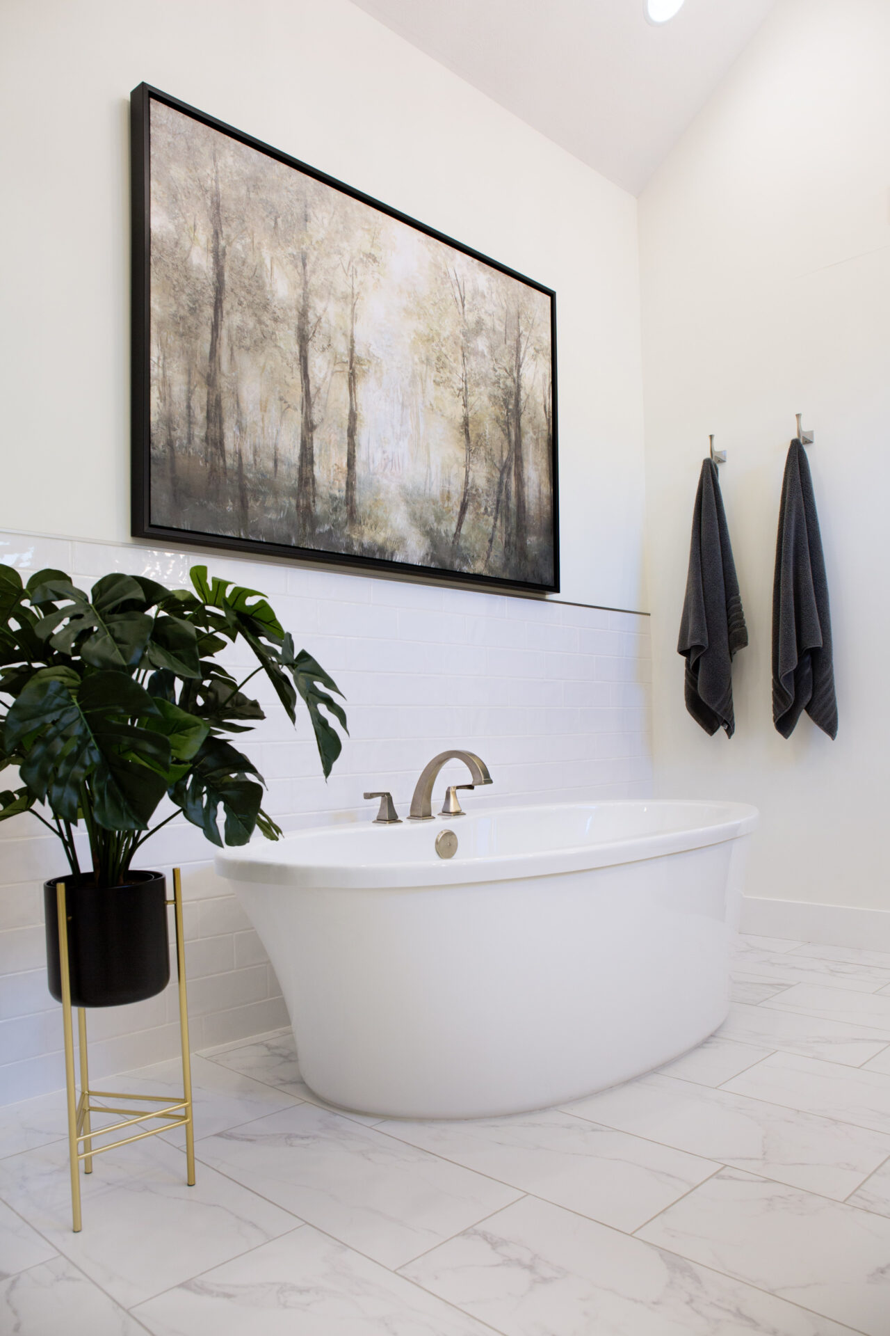 A white bathtub under a painting with a black frame