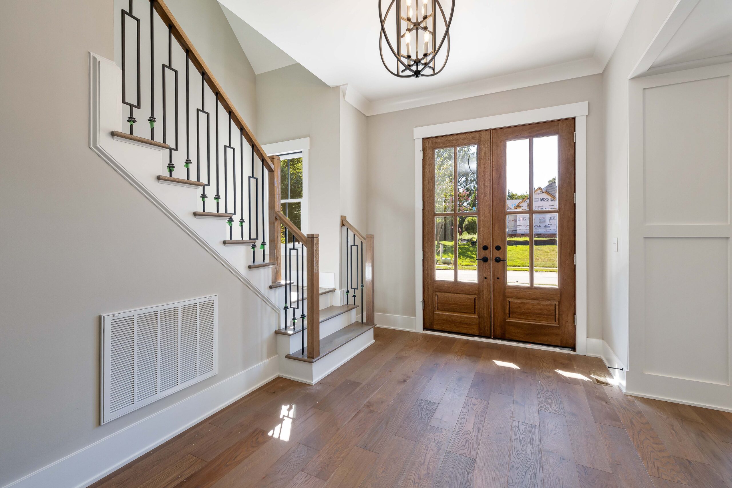 7 Costly Mistakes to Avoid When Building a Custom Home in Springfield 2 Elegant and spacious house entrance featuring wooden doors and staircase.